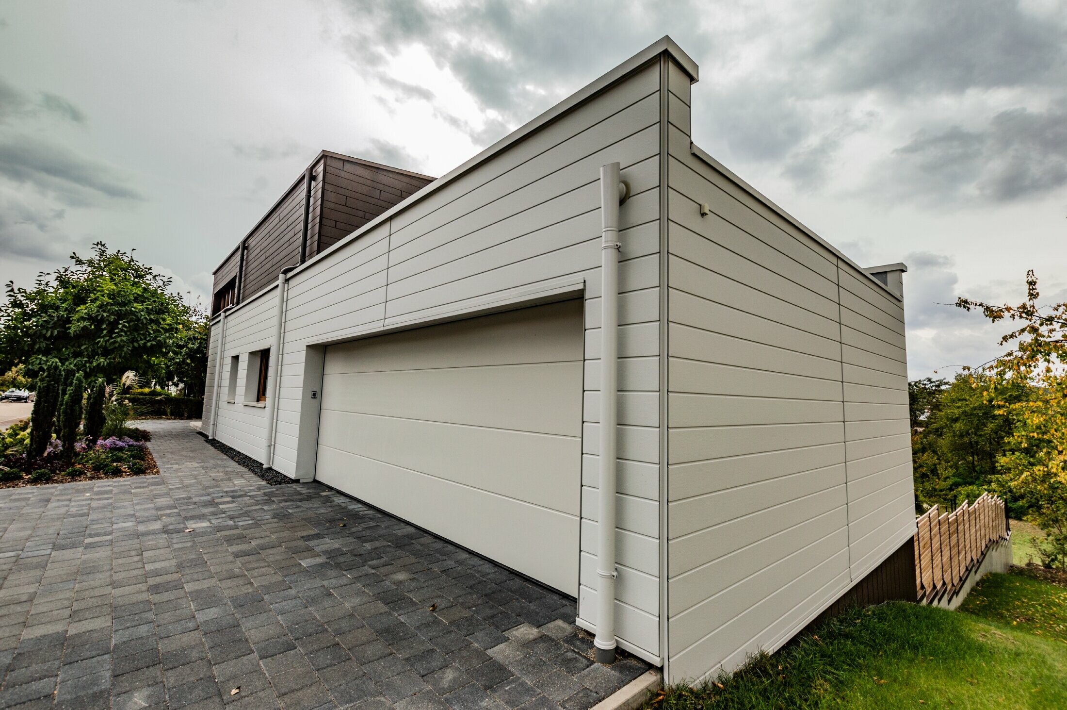 Habillage de garage avec le Siding PREFA en blanc posé à l’horizontale avec l’embranchement d’évacuation PREFA.