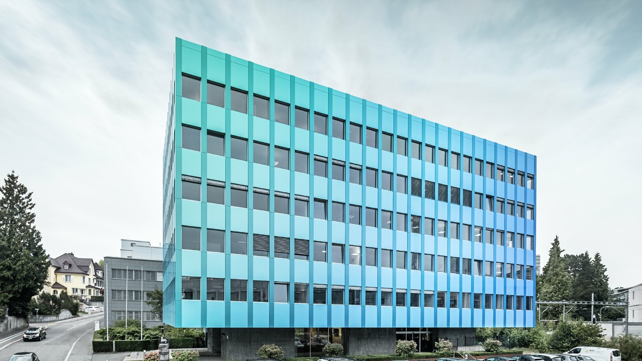 seitliche Ansicht des Wielandhauses in Aarau; Die Fassade ist mit der PREFABOND Verbundplatte aus Aluminium von PREFA verkleidet, die durch das besondere Beschichtungsverfahren in Blau-grün schimmert
