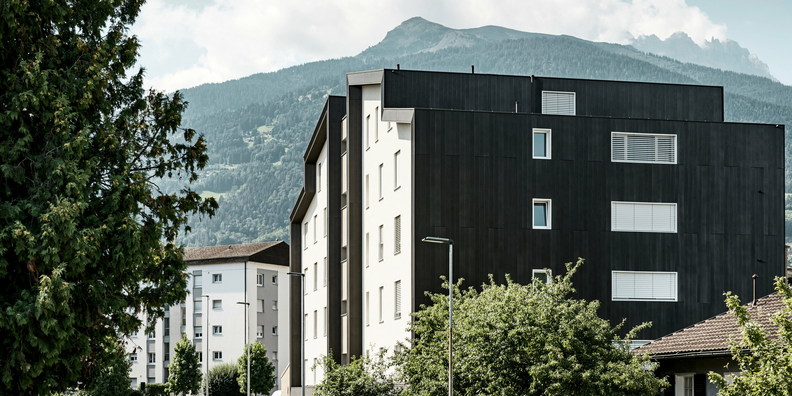 Die Fassade der Wohnhausanlage Les Dailles wurde großflächig mit dem eindrucksvollen PREFA Zackenprofil in Bronze verkleidet. Das Dach des Gebäudes wurde mit PREFALZ in Bronze eingedeckt.