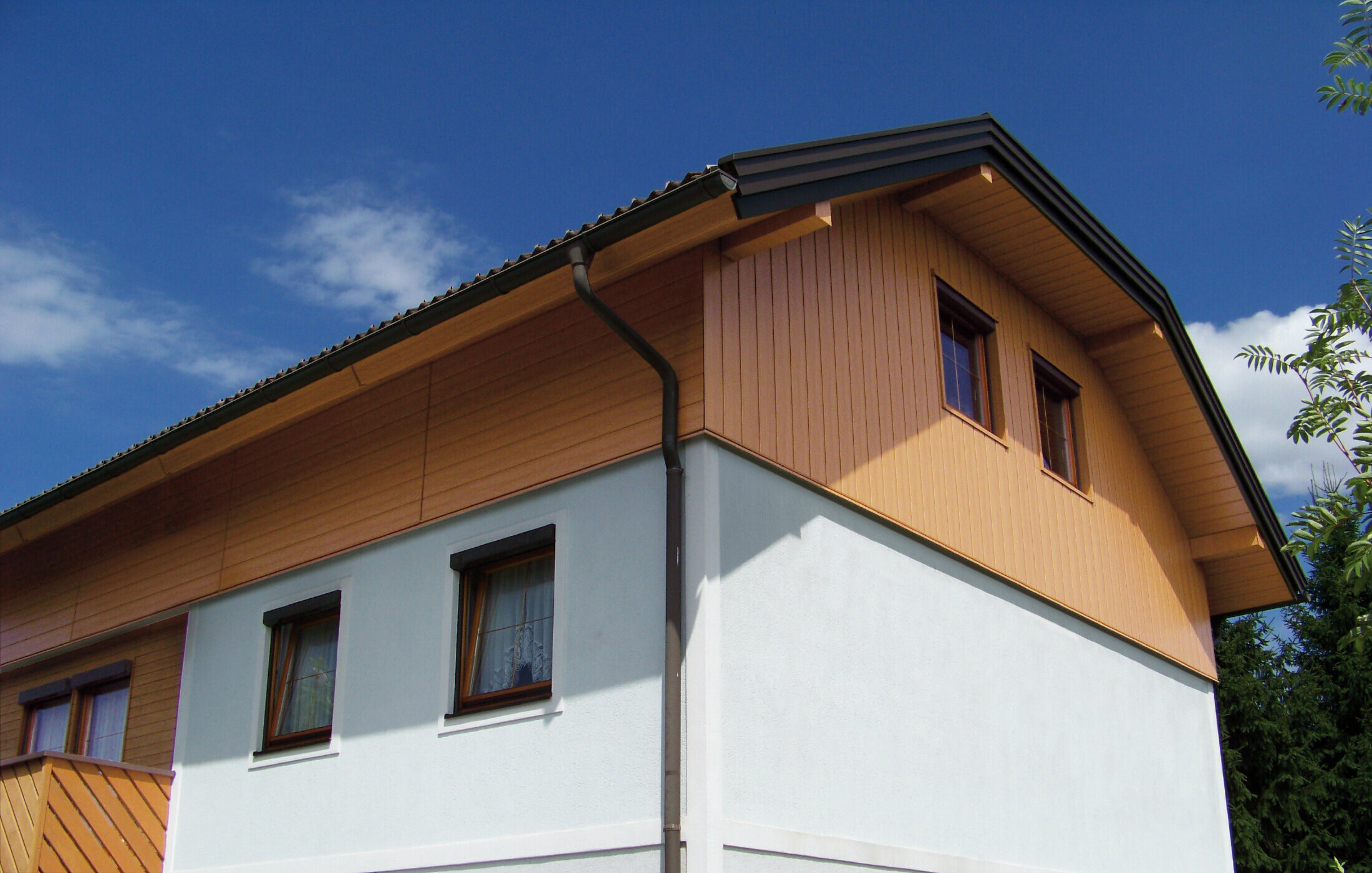 Grande maison individuelle à toit à demi-croupe et revêtement des pignons avec des Sidings PREFA imitation bois clair
