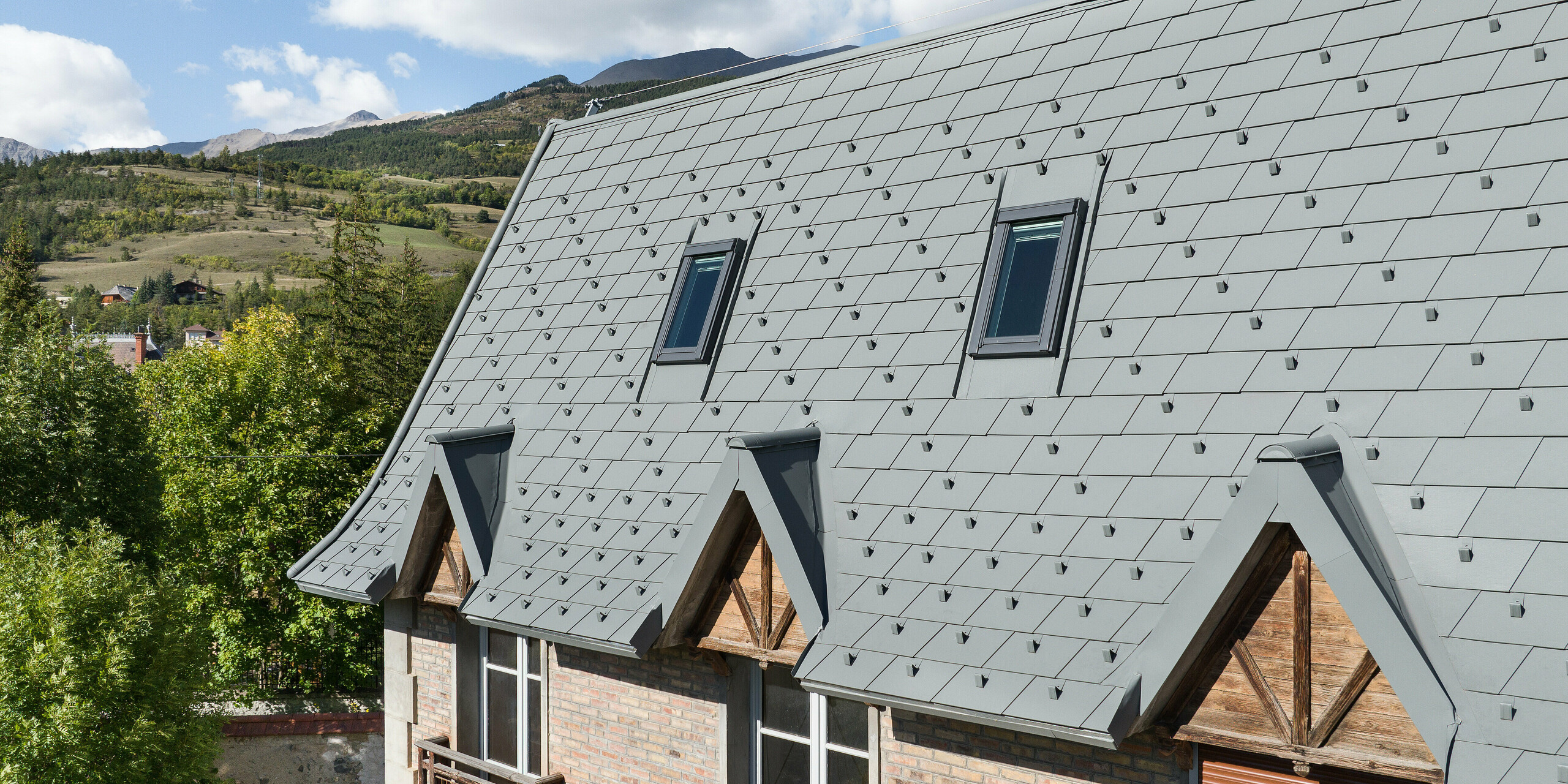 La vaste toiture d'une propriété à Barcelonnette, en France, a été rénovée avec le bardeau de toiture PREFA en P.10 gris souris.