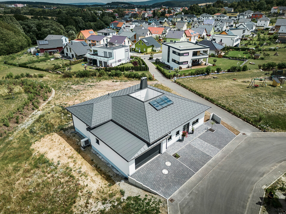 PREFA Dachplatte R.16 und PREFALZ sowie Ablaufrohr und Hängerinne in P.10 Dunkelgrau auf dem Dach eines Bungalows